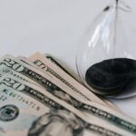 close up photo of hourglass and american paper bills
